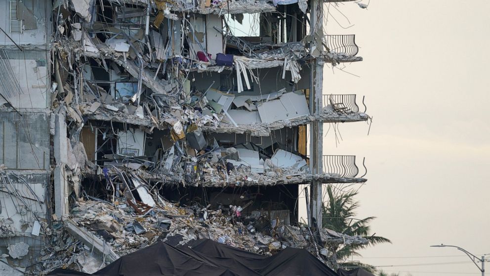 FILE - A giant tarp, bottom, covers a section of rubble where search and rescue personnel have been working at the Champlain Towers South condo building in Surfside, Fla., on July 4, 2021. Money from the sale of Florida beachfront property where the 