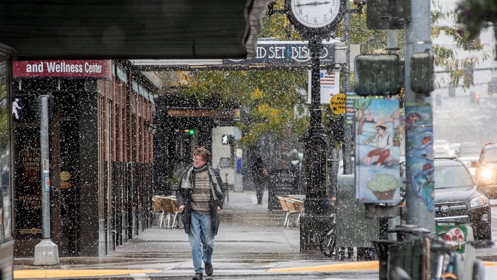 FILE - In this Sept. 29, 2019 file photo, a pedestrian crosses Front Street under snowfall in Missoula, Mont. Under a new proposal, a metro area would have to have at least 100,000 people to count as an MSA, double the 50,000-person threshold that ha