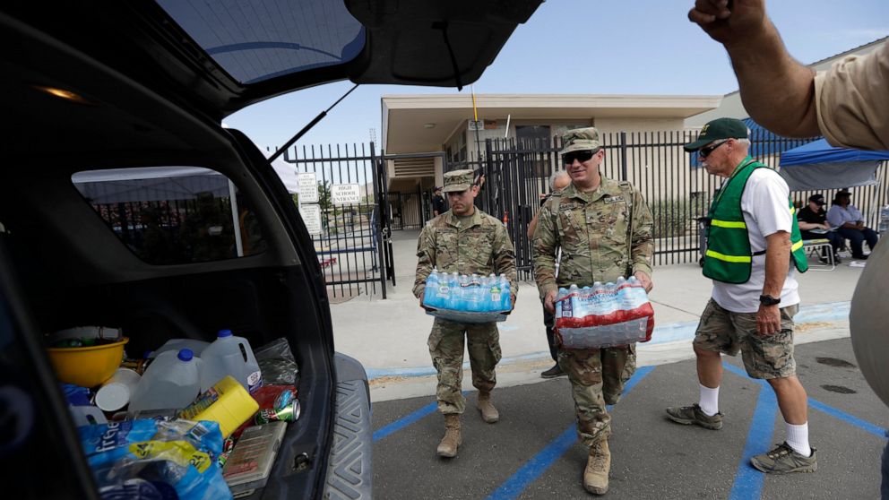 Members of the National Guard load water onto an SUV in the aftermath of an earthquake Sunday, July 7, 2019, outside Trona High School in Trona, Calif. (AP Photo/Marcio Jose Sanchez)