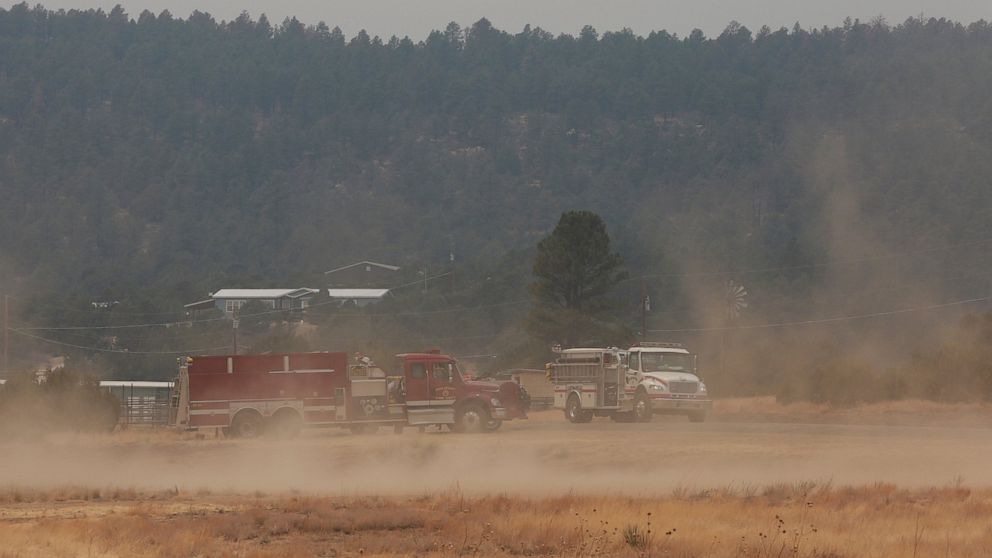 Wind kicks up dust at the fairgrounds as firefighters meet and confer about the wildfire raging on the other side of the hill behind them just outside of Las Vegas, N.M., on Saturday, May 7, 2022. Winds and wildfires have waned in the area allowing s