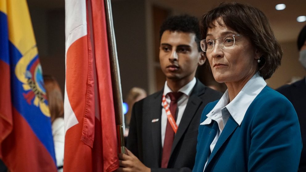 Diplomatic intern Naji Osman, left, holds the Switzerland national flag, as Switzerland's United Nations Ambassador Pascale Baeriswyl, right, prepares for its installation during a ceremony for five newly-elected non-permanent members to serving on t