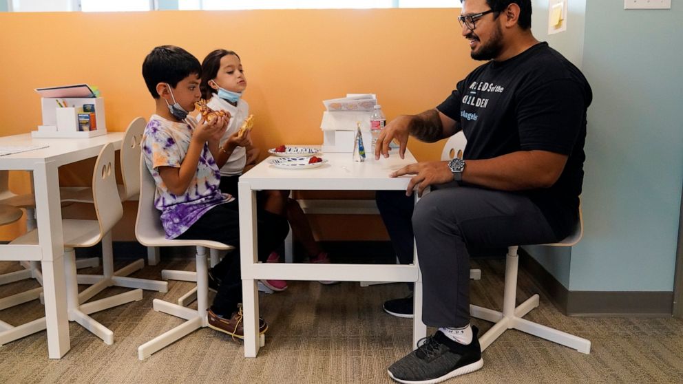 Program Director Alan Arce, right, chats with siblings Moises, left, and Yancy Rodriguez at a Friends of the Children office Wednesday, Aug. 24, 2022, in Lancaster, Calif. Billionaire philanthropist MacKenzie Scott donated $44 million to the Oregon-b