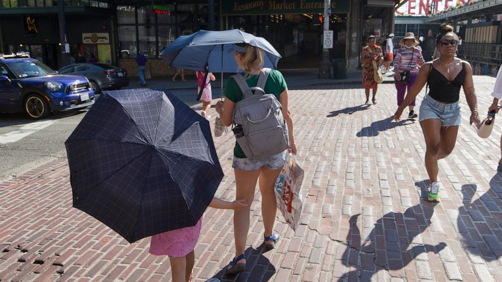 Sabina Ehmann and her daughter Vivian, visiting Seattle from North Carolina, are prepared with umbrellas to shield the sun during a heat wave hitting the Pacific Northwest, Sunday, June 27, 2021, in Seattle. Yesterday set a record high for the day wi