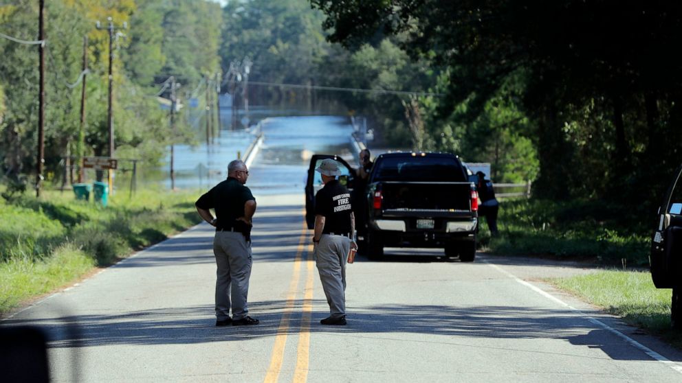 FILE - Responders congregate near where two people drowned when they were trapped in a Horry County Sheriff's transport van while crossing an overtopped bridge over the Little Pee Dee River on Highway 76, during rising floodwaters in the aftermath of