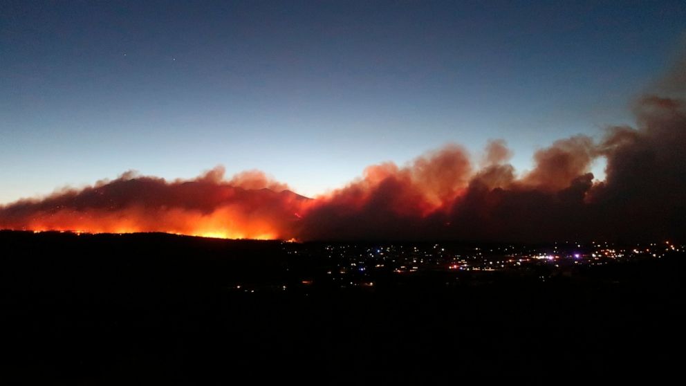 A wildfire burning on the outskirts of Flagstaff, Arizona, Sunday, June 12, casts a glow above neighborhoods. Evacuations have been ordered for homes in the area. Authorities say firefighters are responding to the wildfire about six miles north of Fl