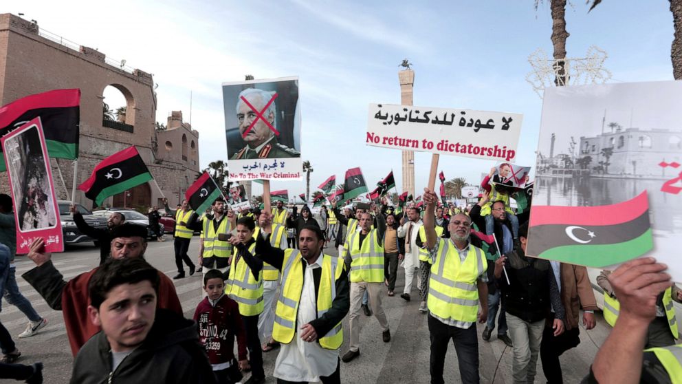 FILE - In this April 19, 2019 file photo, protesters wear yellow vests at a protest as they wave national flags and chant slogans against Libya's Field Marshal Khalifa Hifter, in Tripoli, Libya. Officials in Libya’s U.N.-backed administration say the