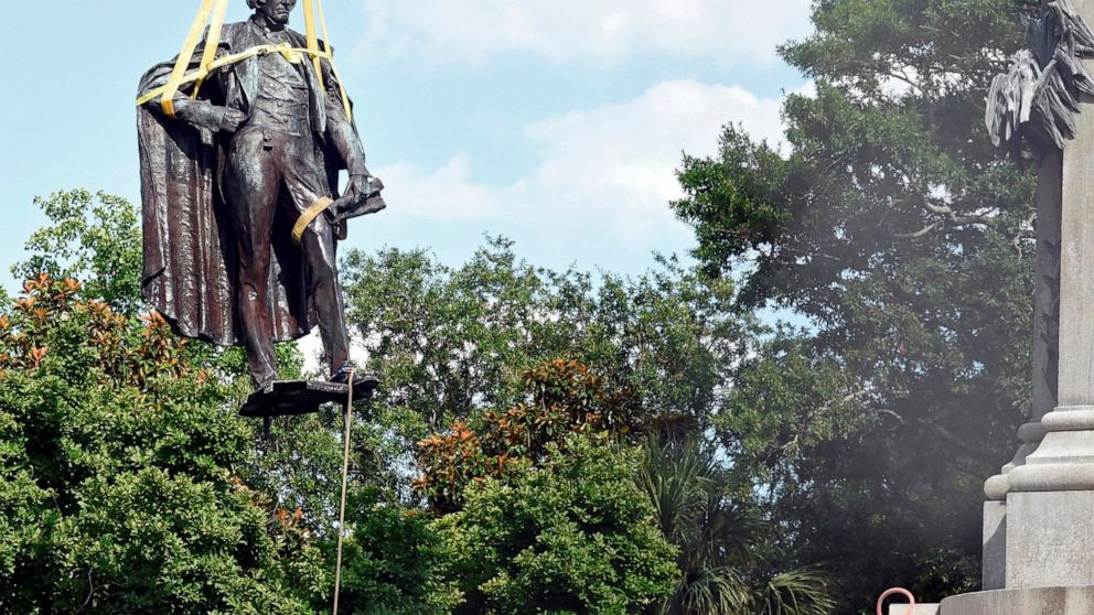 FILE - A statue of former U.S. Vice President and slavery advocate John C. Calhoun is raised by crews after its removal from a 100-foot-tall monument on Wednesday, June 24, 2020, in Charleston, S.C. Lawsuits filed to stop the removal of memorials to 