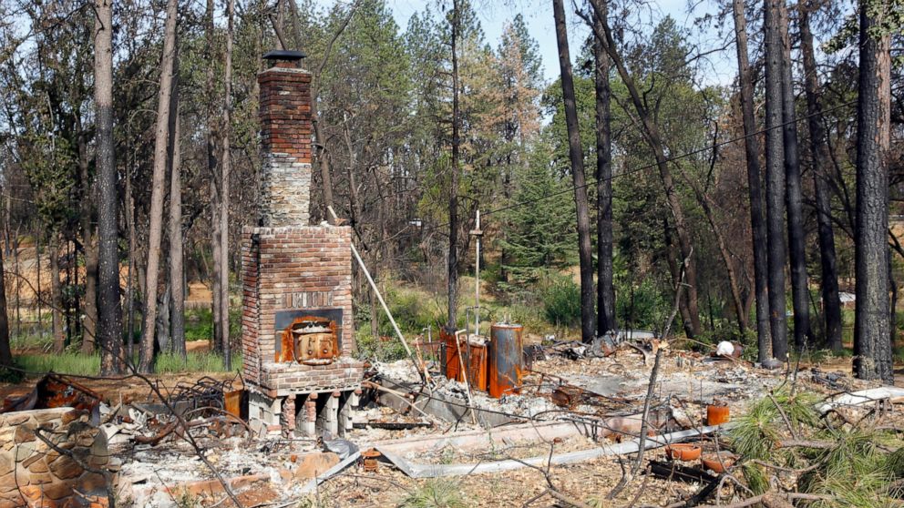 FILE— In this Aug. 21, 2019, file photo, burned trees and vegetation surround the burned-out remains of a home destroyed by the 2018 Camp Fire in Paradise, Calif. Wildfires have destroyed nearly 50,000 homes in California alone in the last five years