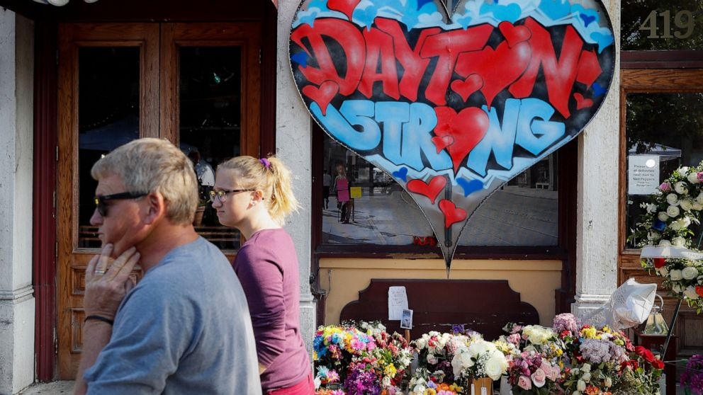 FILE - In this Aug. 7, 2019 file photo, pedestrians pass a makeshift memorial for the slain and injured victims of a mass shooting that occurred in the Oregon District in Dayton, Ohio. The six officers who shot and killed an active shooter in Dayton 