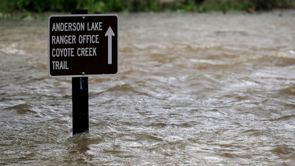 FILE - In this Feb. 21, 2017 file photo a sign is submerged in the water from Coyote Creek in Morgan Hill, Calif. U.S. officials are worried that an earthquake could collapse a big dam near Silicon Valley. They ordered its reservoir to be completely 