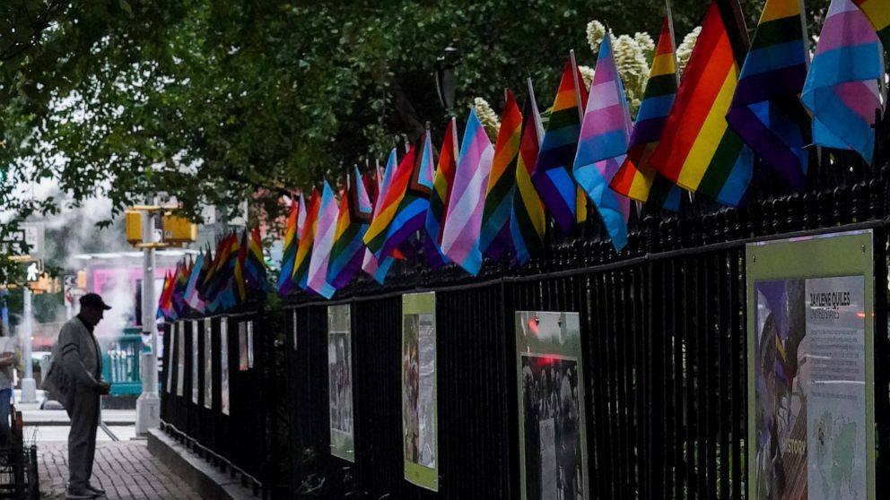 A visitor views a historical exhibit of the Gay rights movement, displayed on fencing dressed with flags affirming LGBTQ identity at the Stonewall National Monument, Wednesday, June 22, 2022, in New York. Sunday's Pride Parade wraps a month marking t