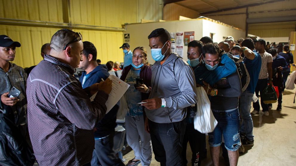People line up for a commercial bus that will take them to the San Antonio airport at a warehouse run by the Mission: Border Hope nonprofit group run by the United Methodist Church in Eagle Pass, Texas, May 23, 2022. The Border Patrol releases up to 