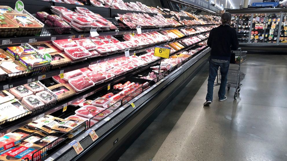 FILE - In this May 10, 2020 file photo, a shopper pushes his cart past a display of packaged meat in a grocery store in southeast Denver. Prices at the wholesale level fell from June to July, the first month-to-month drop in more than two years and a