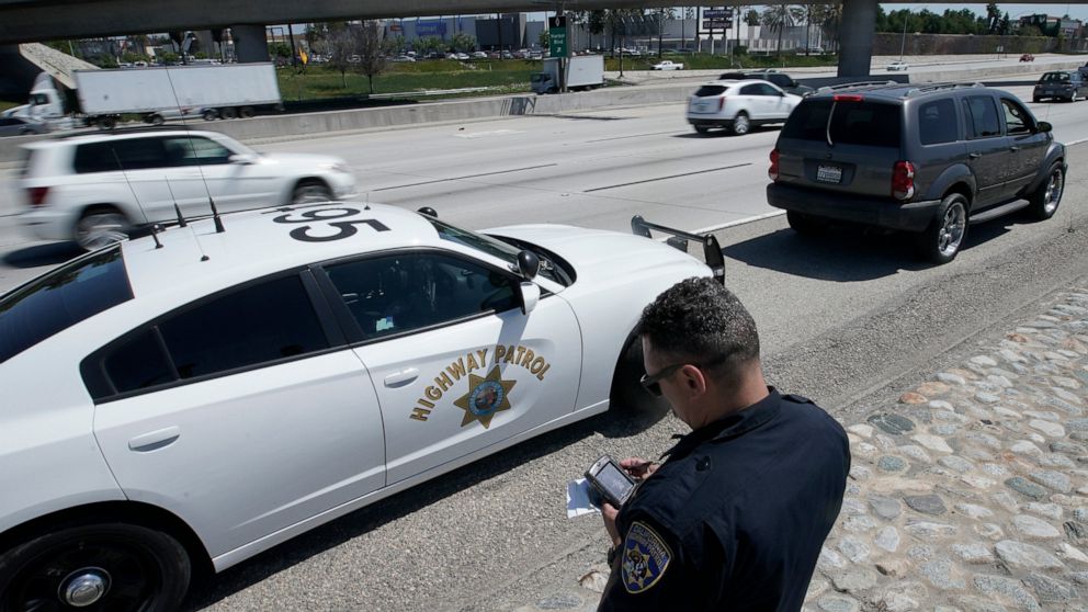 FILE - California Highway Patrol officer Troy Christensen runs a driver's license after stopping a motorist along Interstate 5 who was suspected of speeding on April 23, 2021, in Anaheim, Calif. The U.S. government's road safety agency said Tuesday, 