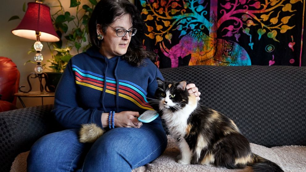 Tara Kramer sits in her apartment with her cat Busy, Friday, April 8, 2022, in Des Moines, Iowa. Month by month, more of the roughly 40 million Americans who get help buying food through the federal SNAP program are seeing their benefits plunge even 