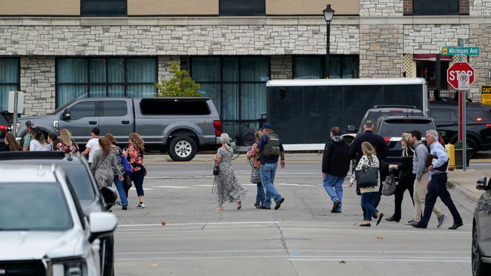 Police evacuate people from buildings near the Hampton Inn in Dearborn, Mich., Thursday, Oct. 6, 2022. Police negotiated Thursday afternoon with a suspected gunman inside the suburban Detroit hotel after reports of gunfire led to evacuations and lock