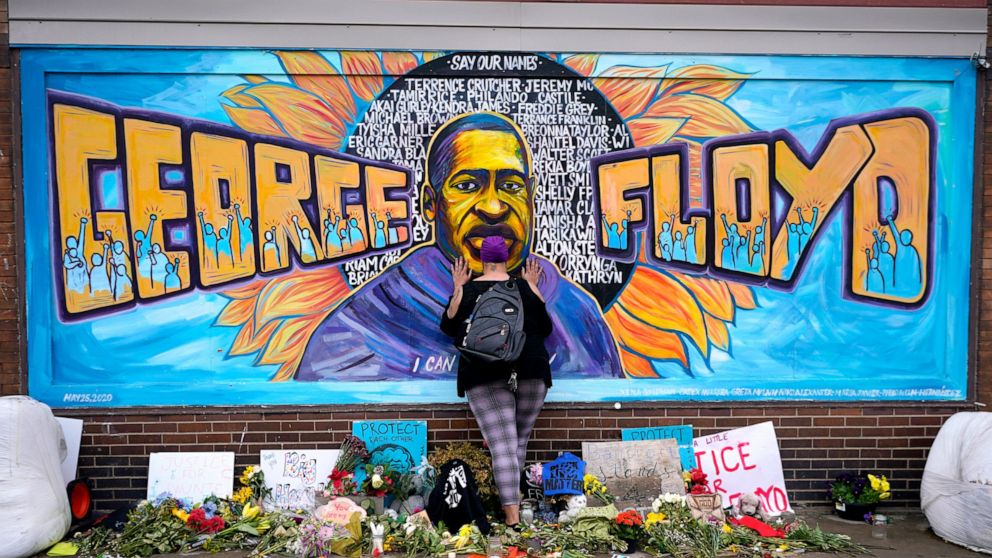 FILE - Damarra Atkins pays respect to George Floyd at a mural at George Floyd Square in Minneapolis, April 23, 2021. Minneapolis will buy the boarded-up Speedway gas station at George Floyd Square, the City Council decided unanimously on Thursday, De