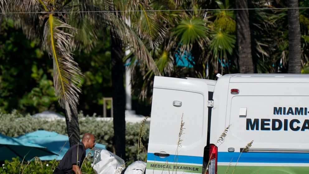 Workers load a stretcher with remains extricated from the rubble into a Miami-Dade County Medical Examiner van, near the Champlain Towers South condo building, where scores of people remain missing more than a week after it partially collapsed, Frida