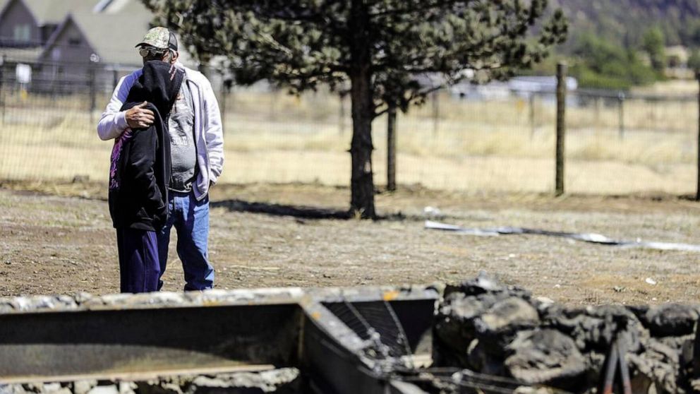Edward Leazier comforts Sheila Dobson as the two survey what is left of their family home on Monday, April 25, 2022, after the Tunnel Fire burned through the community east of Flagstaff, Ariz., off of Brandis Way. Residents are just now being let bac