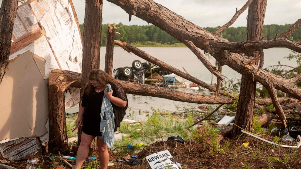 This photo provided by the U.S. Navy, Missy Lattanzie, an RV park resident, searches through her belongings that were destroyed after a tornado touched down Wednesday on Naval Submarine Base Kings Bay, on Thursday, July 8, 2021 in Kings Bay, Ga. Seve