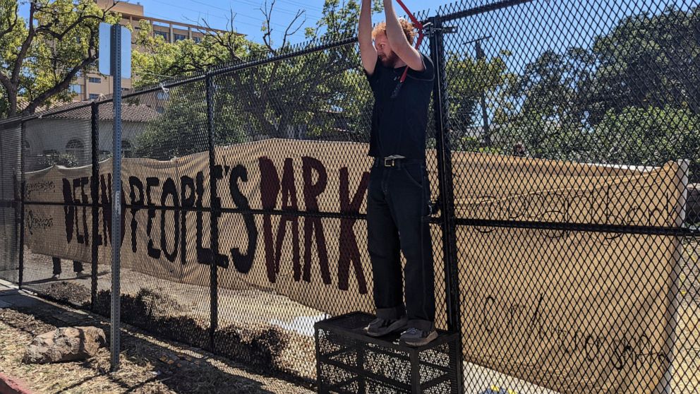 FILE - A protester uses bolt cutters to take down part of the fence that the University of California, Berkeley, erected around historic People's Park, Aug. 3, 2022, so a construction crew could begin work on a long-planned student housing project in