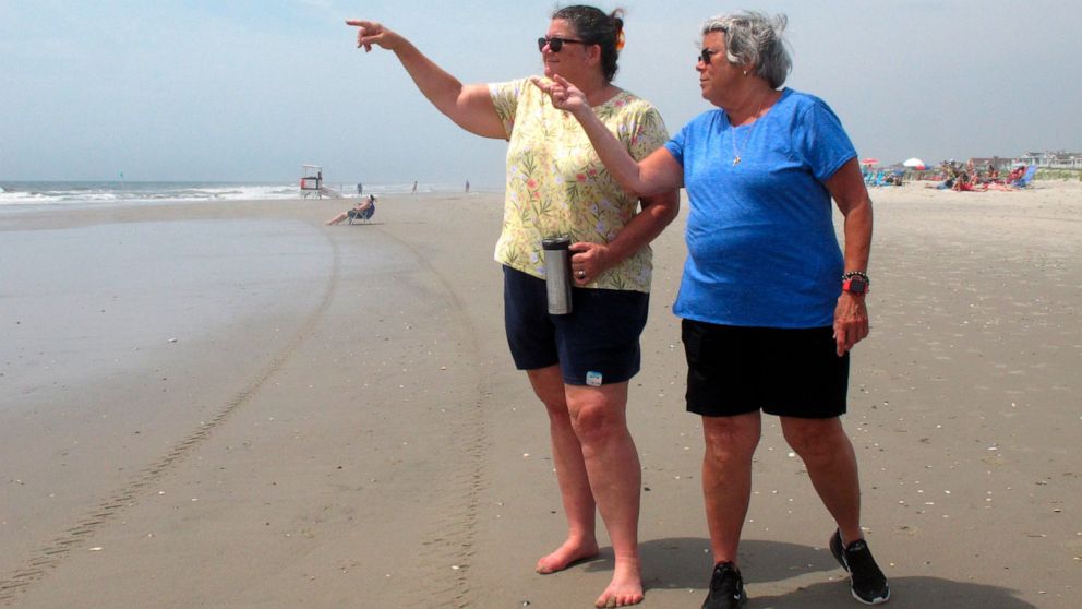 Suzanne Hornick, left, and Susan Cox, right, look out to sea from a beach in Ocean City N.J. on July 8, 2021 where power cables from an offshore wind farm are projected to come ashore. They are among opponents of offshore wind who question its impact