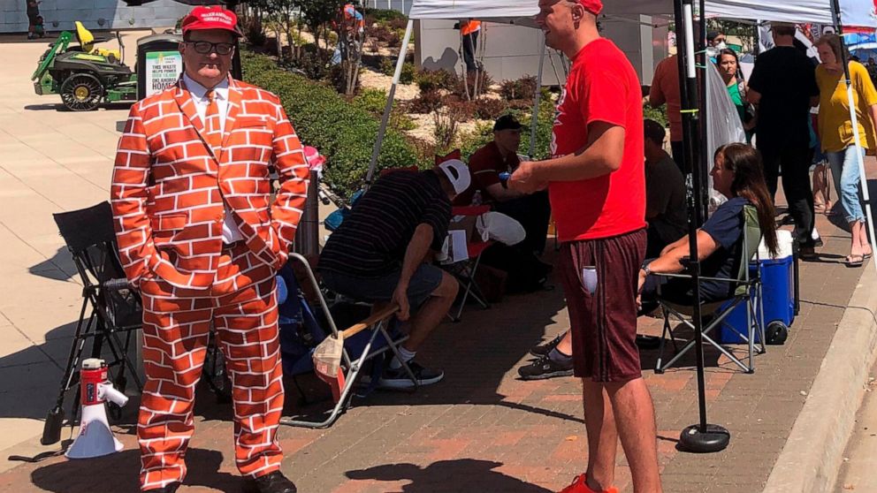 Supporters of President Trump, including a man dressed as the border wall, line up outside outside an arena in Tulsa, Oklahoma, June 18, 2020, where the president will hold his first campaign rally in months this weekend .Despite the heat, the ever-g
