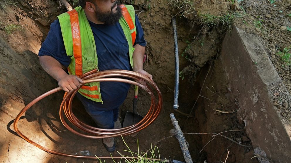 FILE - A worker with Denver Water prepares to pass a new copper water service line from a residential water meter to the water main June 17, 2021, in Denver. The Environmental Protection Agency on Thursday, Dec. 1, 2022, approved a nearly $700 millio