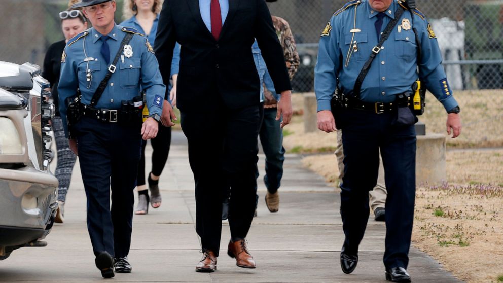 Arkansas State Troopers escort former Lonoke County sheriff's deputy, Michael Davis, center, into the Cabot Readiness Center in Cabot, Ark., on Tuesday, March 15, 2022. A jury was seated Tuesday in the trial of Davis, a former Arkansas deputy charged