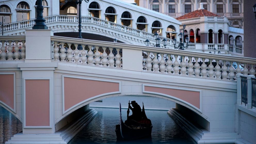 FILE - A gondolier steers his boat beneath a quiet pedestrian walkway at the Venetian hotel and casino in Las Vegas on Feb. 4, 2021. The new and old owners of the Venetian and Palazzo casino resorts and former Sands Expo and Convention Center announc