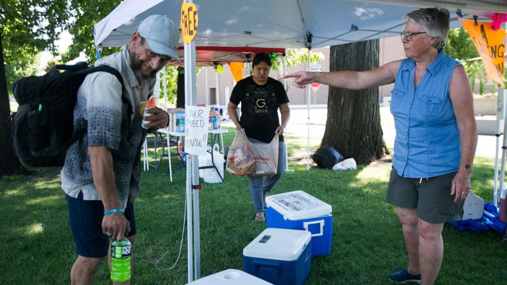Betsy Martin, a volunteer with Yakima Community Aid, right, helps Chance Lorez, left, pack water and a sports drink Monday, June 28, 2021, at a cooling station in Yakima, Wash. (Amanda Ray /Yakima Herald-Republic via AP)