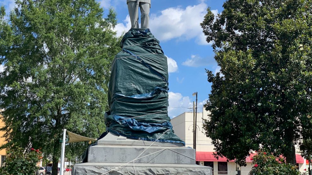 FILE - A Confederate monument in Tuskegee, Ala., is shown with its base wrapped in tarps on June 12, 2020. A Confederate heritage group is fighting an Alabama county's lawsuit that could lead to the removal of the rebel monument in the heart of nearl