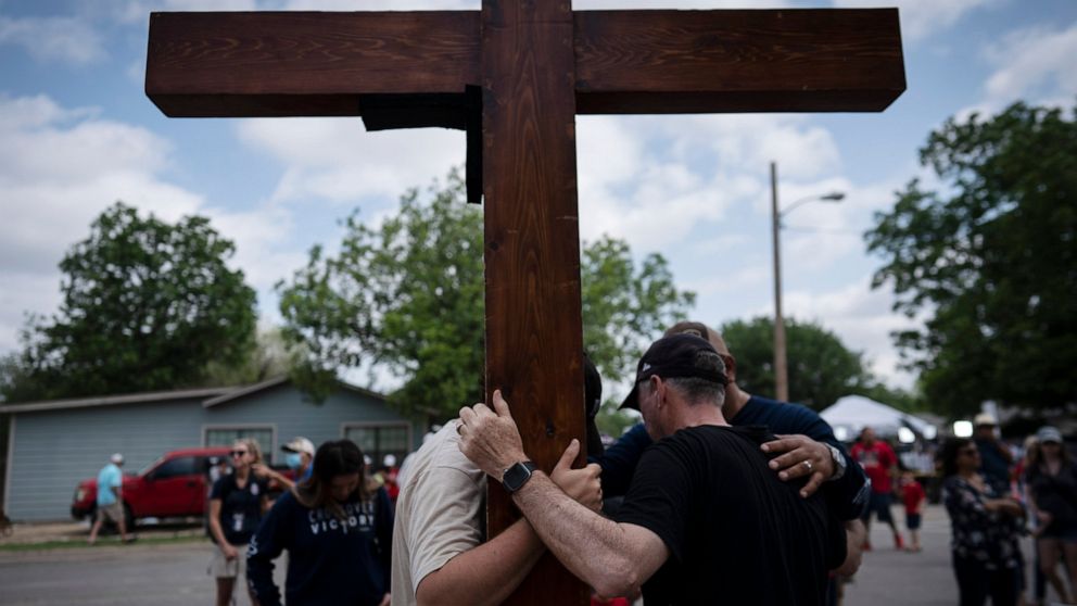Dan Beazley, right, with his son Joey Beazley, from Detroit, carry their wooden cross as they pray at a memorial outside Robb Elementary School in Uvalde, Texas, Monday, May 30, 2022. Multiple people were killed by an 18-year-old gunman at the school