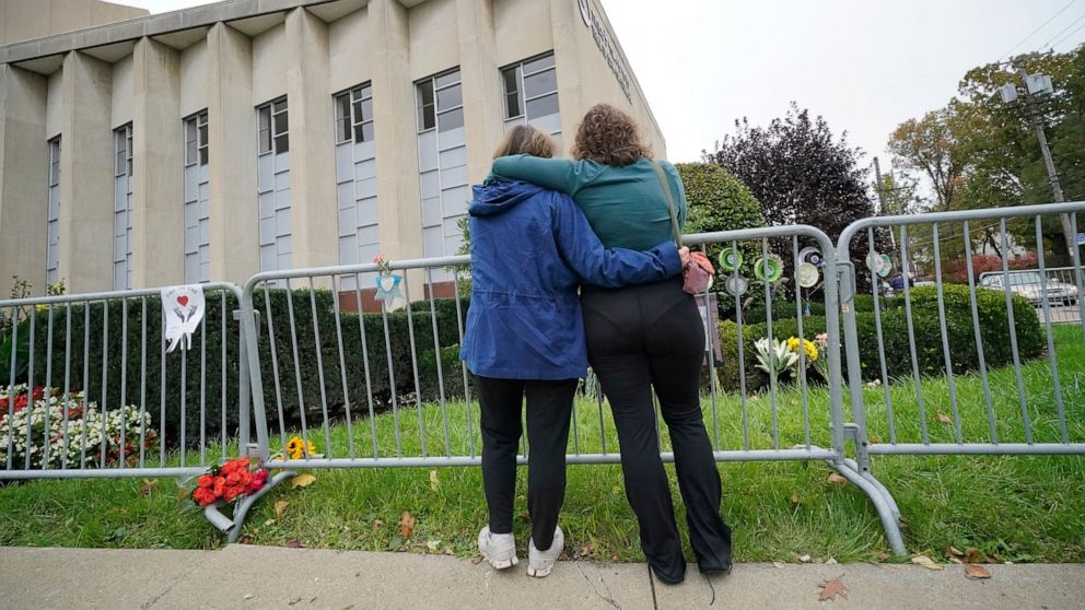 FILE - Two women pause along a fence outside the dormant landmark Tree of Life synagogue in Pittsburgh's Squirrel Hill neighborhood on Wednesday, Oct. 27, 2021. The long-delayed capital murder trial of Robert Bowers in the 2018 Pittsburgh synagogue m