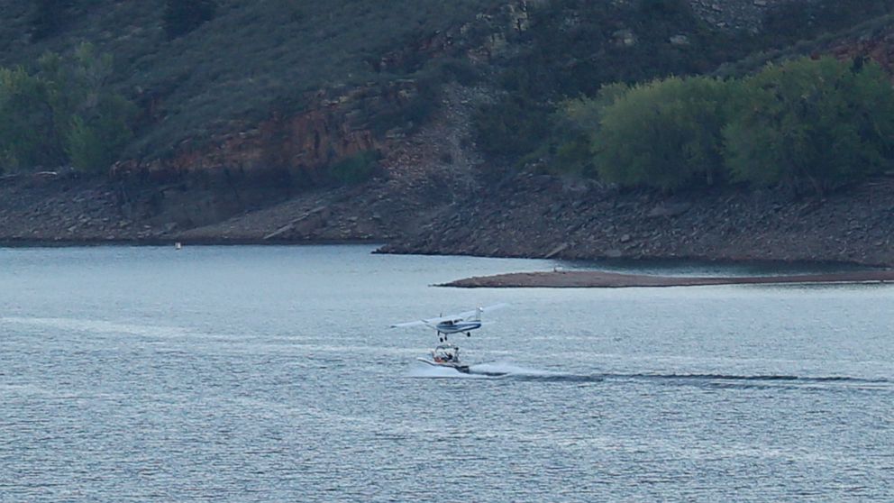 In this image provided by Stephanie Stamos, a small plane flies closely over a boat in a Northern Colorado reservoir before it crashed near Fort Collins, Colo., Sunday Sept. 11, 2022. Law-enforcement officials said two people in the single-engine pla