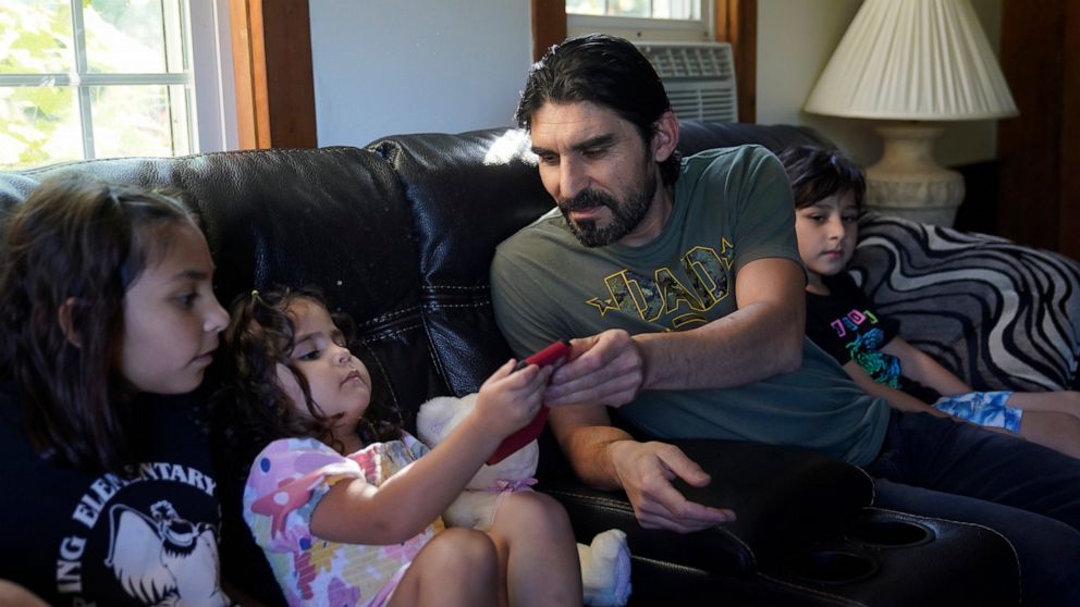 Mohammad Walizada, center right, who fled Afghanistan with his family, sits with three of his children, from the left, Zahra, 10, Hasnat, 3, and Mohammad Ibrahim, 7, Thursday, Sept. 15, 2022, at their home, in Epping, N.H. Since the U.S. military's w