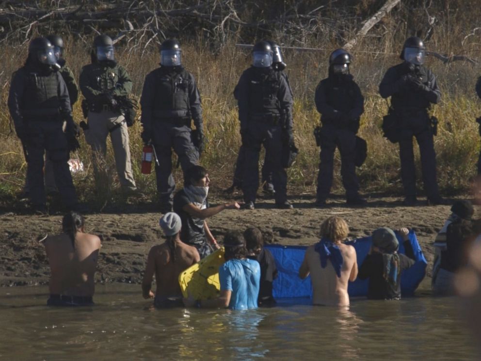PHOTO: Danny Grassrope, a member of the International Indigenous Youth Council, urges protesters to remain in prayer during a confrontation with law enforcement.