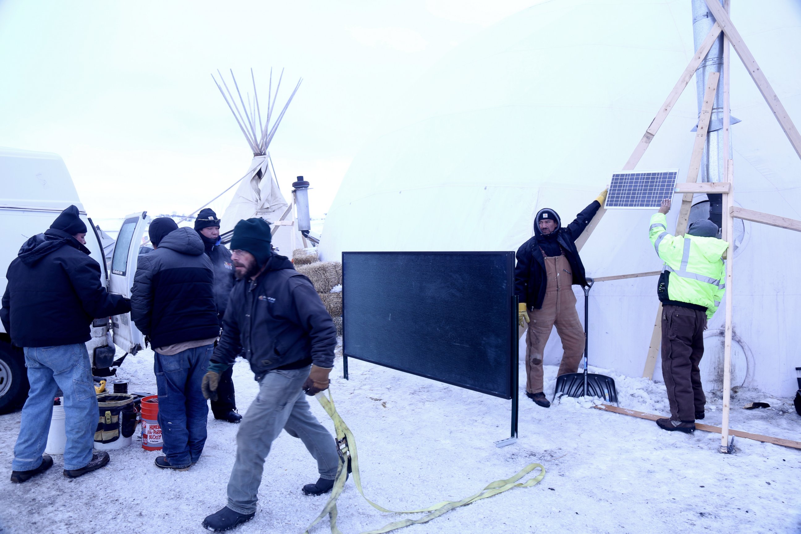 PHOTO: Terry Spoonhunter (second from right) and Silas Red Cloud (right) hold up a solar panel at the Oceti Sakowin Camp on the Standing Rock Reservation in Cannon Ball, North Dakota, Dec. 21, 2016. 