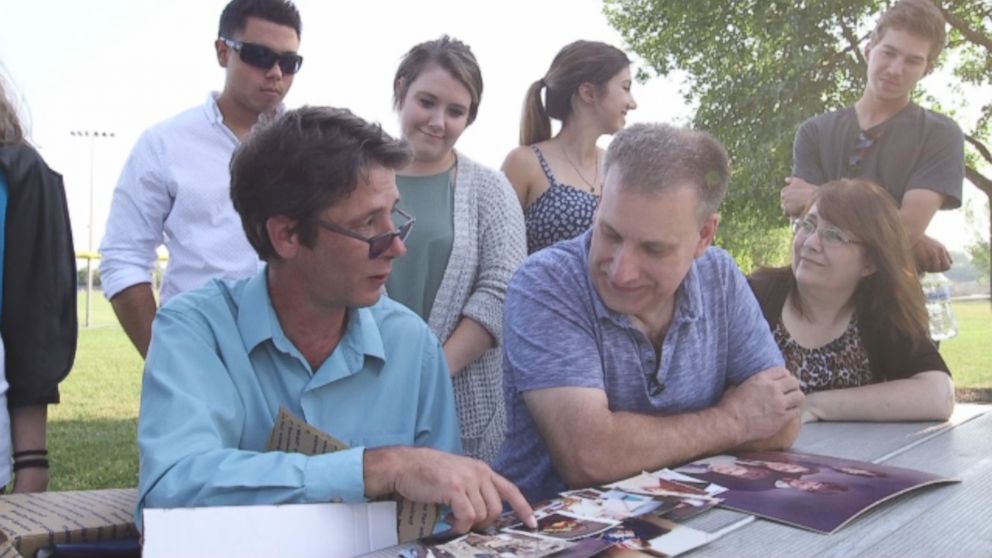 Half-brothers Bill Gillespie (right) and Ken Cummins (left) look at family photos together after meeting for the first time in decades. 