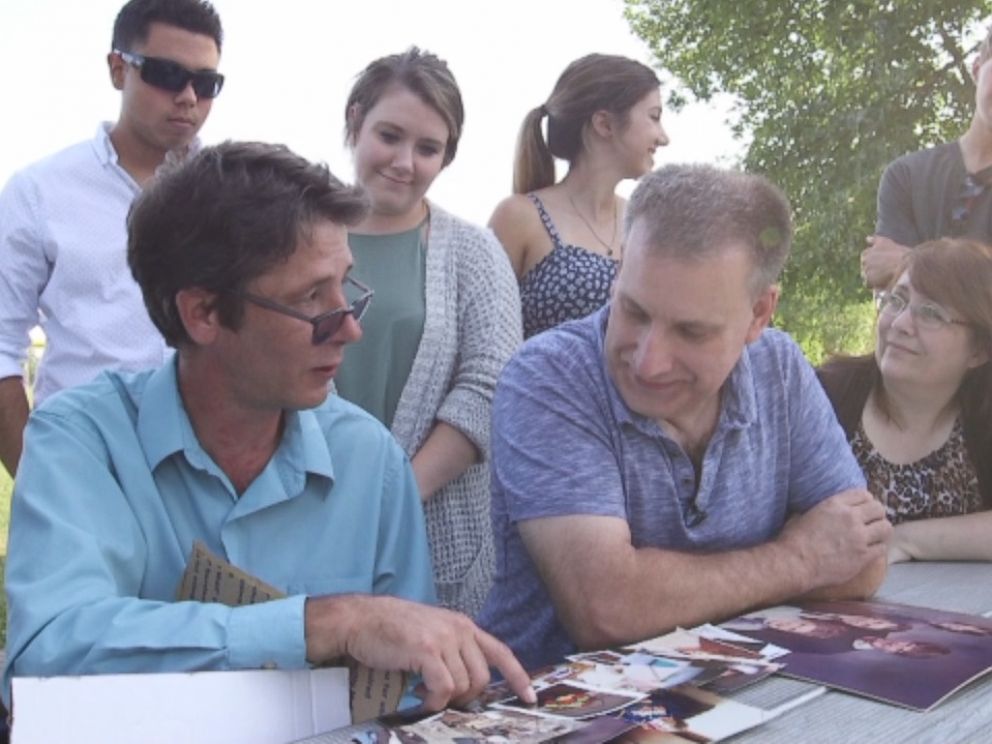 Half-brothers Bill Gillespie (right) and Ken Cummins (left) look at family photos together after meeting for the first time in decades.