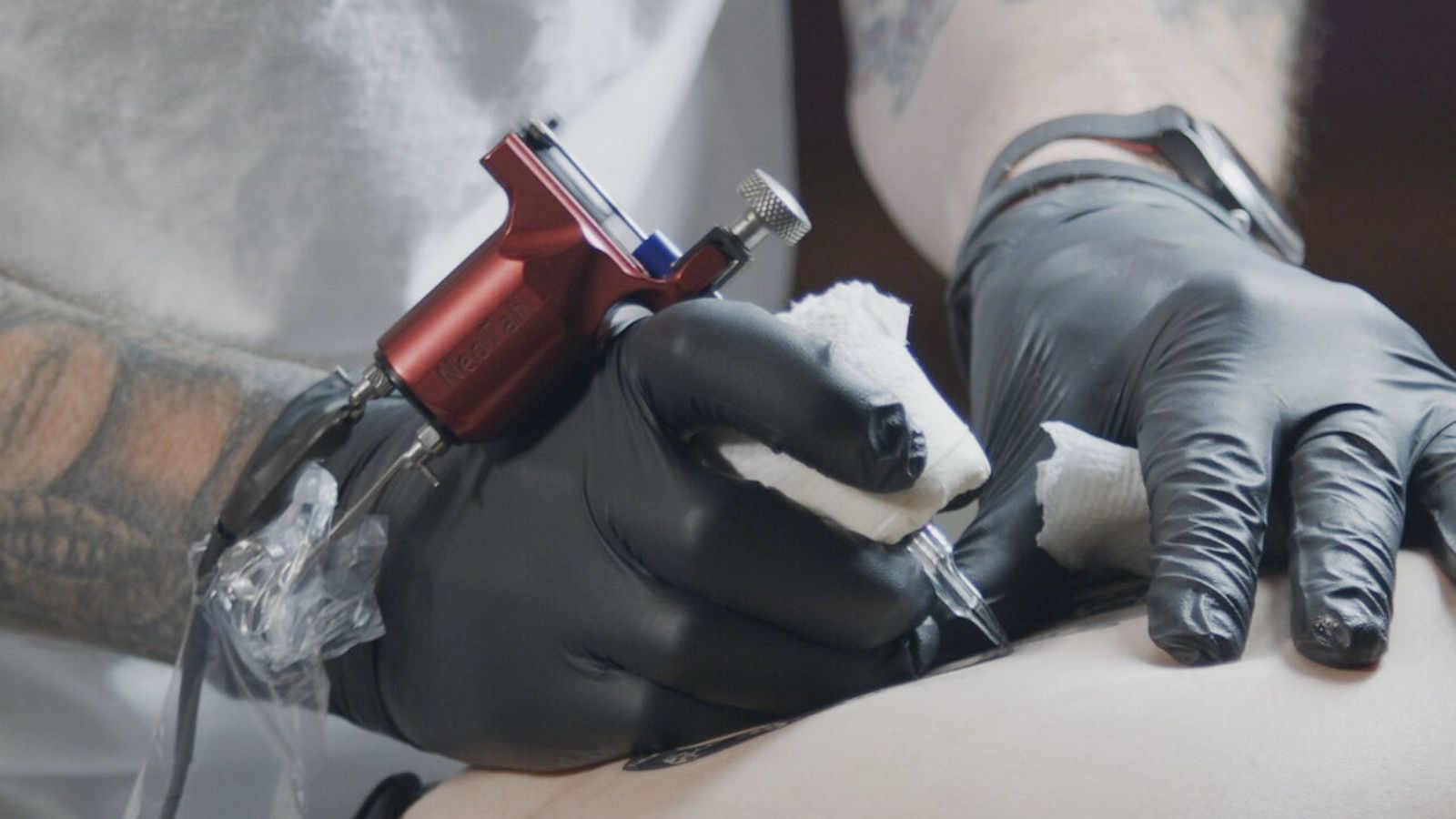 Tattoo artist at work Woman in black latex glove tattooing a young mans  hand with colorful picture in studio Close up Stock Photo  Alamy