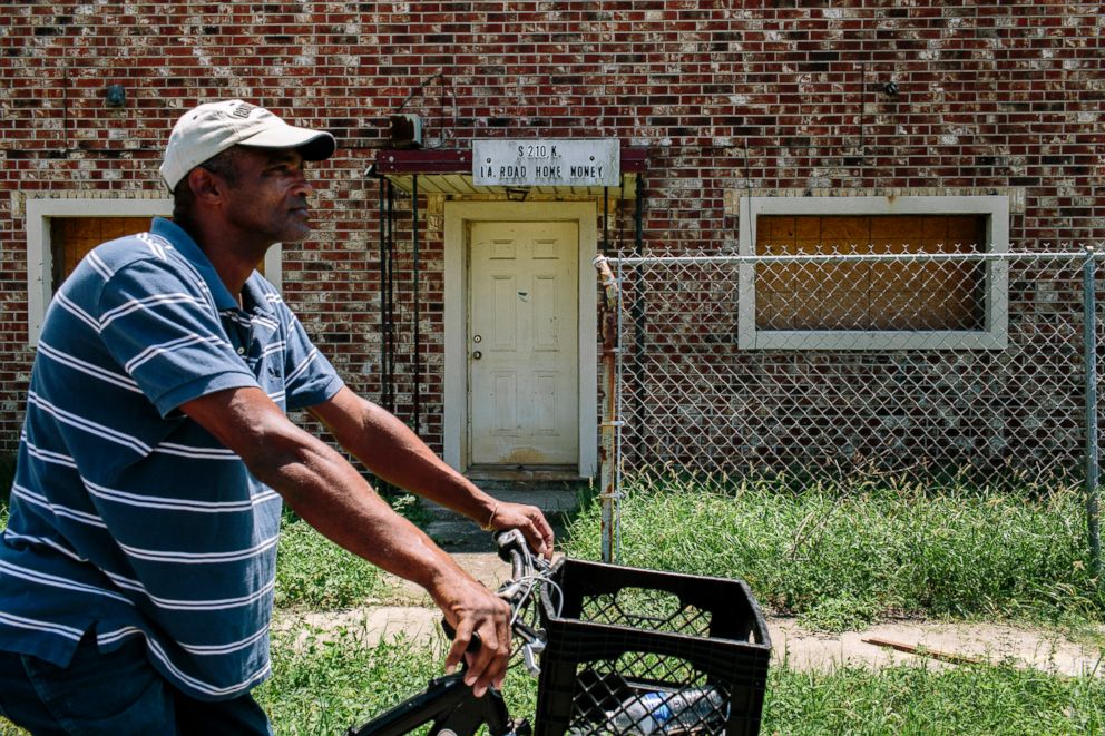 PHOTO: Adrian Caliste, 54, pauses on his bicycle in front of a house in the Upper Ninth Ward, near the location where the West side of the Industrial Canal breached and flooded the neighborhood 10 years ago.
