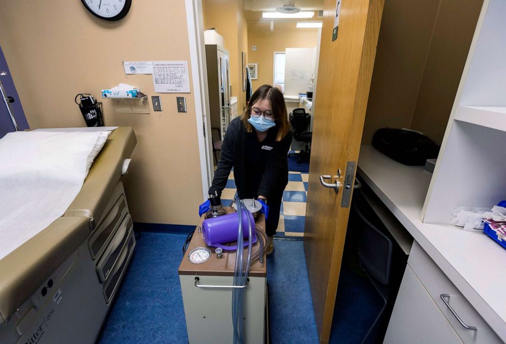 PHOTO: A lab assistant transports a suction machine into a patient room, on July 7, 2022, at WE Health Clinic in Duluth, Minn.