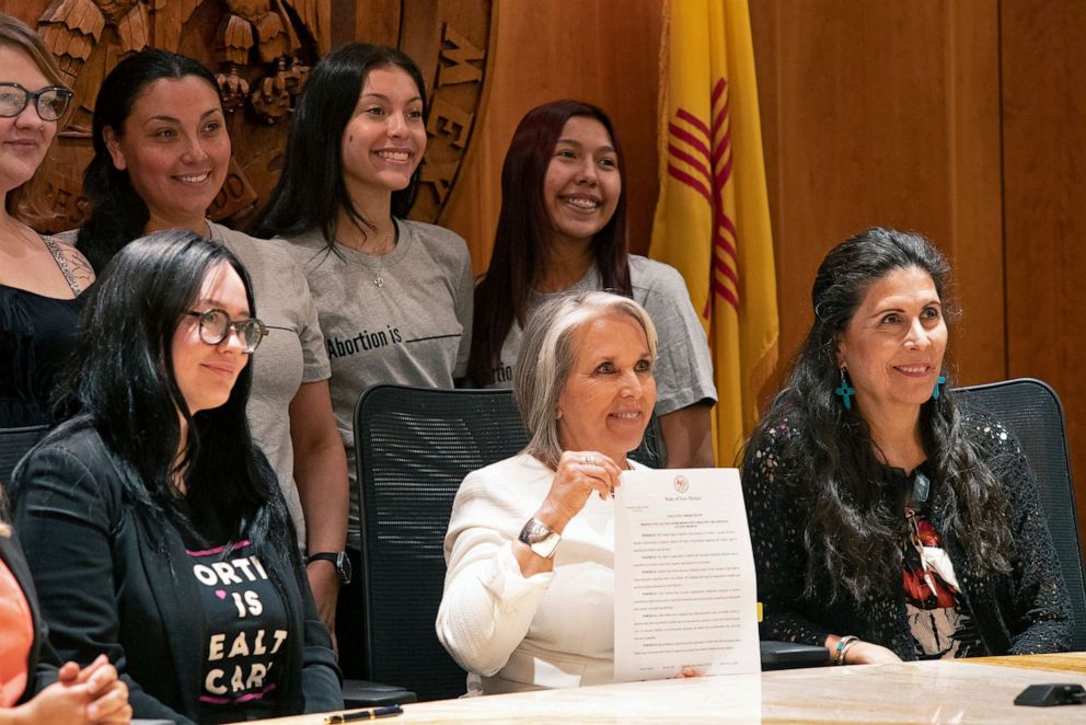PHOTO: Gov. Michelle Lujan Grisham, center holds the Executive Order to protect access to Abortion in New Mexico after a signing ceremony on June 27, 2022, in Albuquerque, N.M. At right is Senator Linda Lopez. 