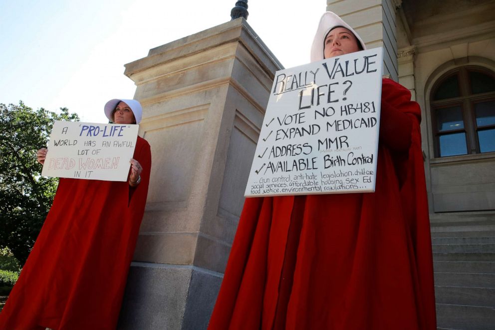 PHOTO: April Houston and Lara Martin hold signs while dressed as Handmaids in protest of Georgia's anti-abortion "heartbeat" bill at the Georgia State Capitol in Atlanta, May 7, 2019.  