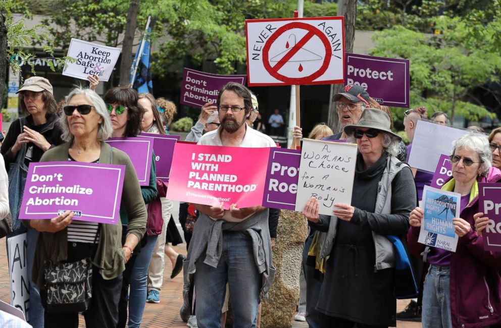 PHOTO: Demonstrators hold signs, July 10, 2018, as they listen to a speaker during a protest in Seattle against President Donald Trump and his choice of federal appeals Judge Brett Kavanaugh as his second nominee to the Supreme Court. 