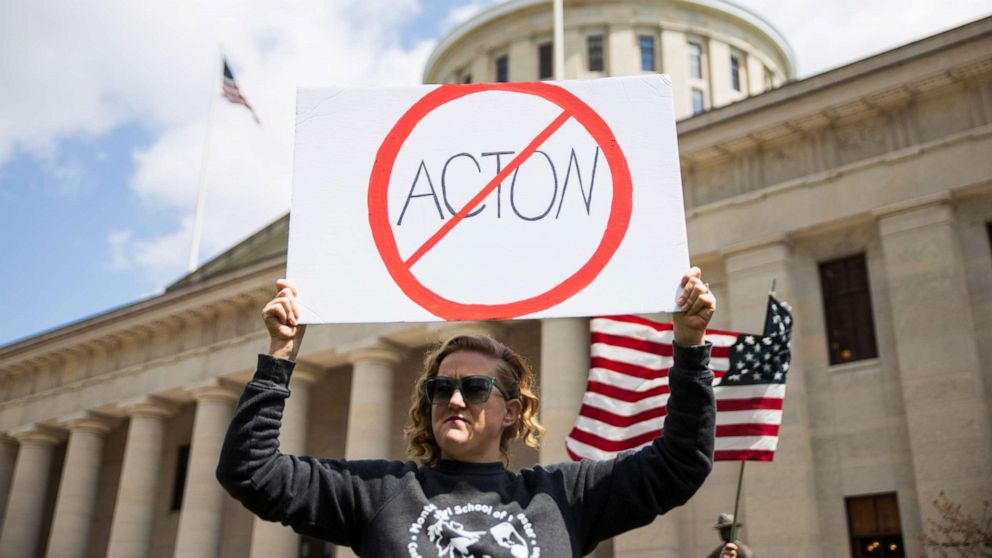 PHOTO: A woman holds up a sign against Dr. Amy Acton outside of the Ohio State House in Columbus, Ohio on April 18, 2020, to protest the stay home order that is in effect until May 1st.