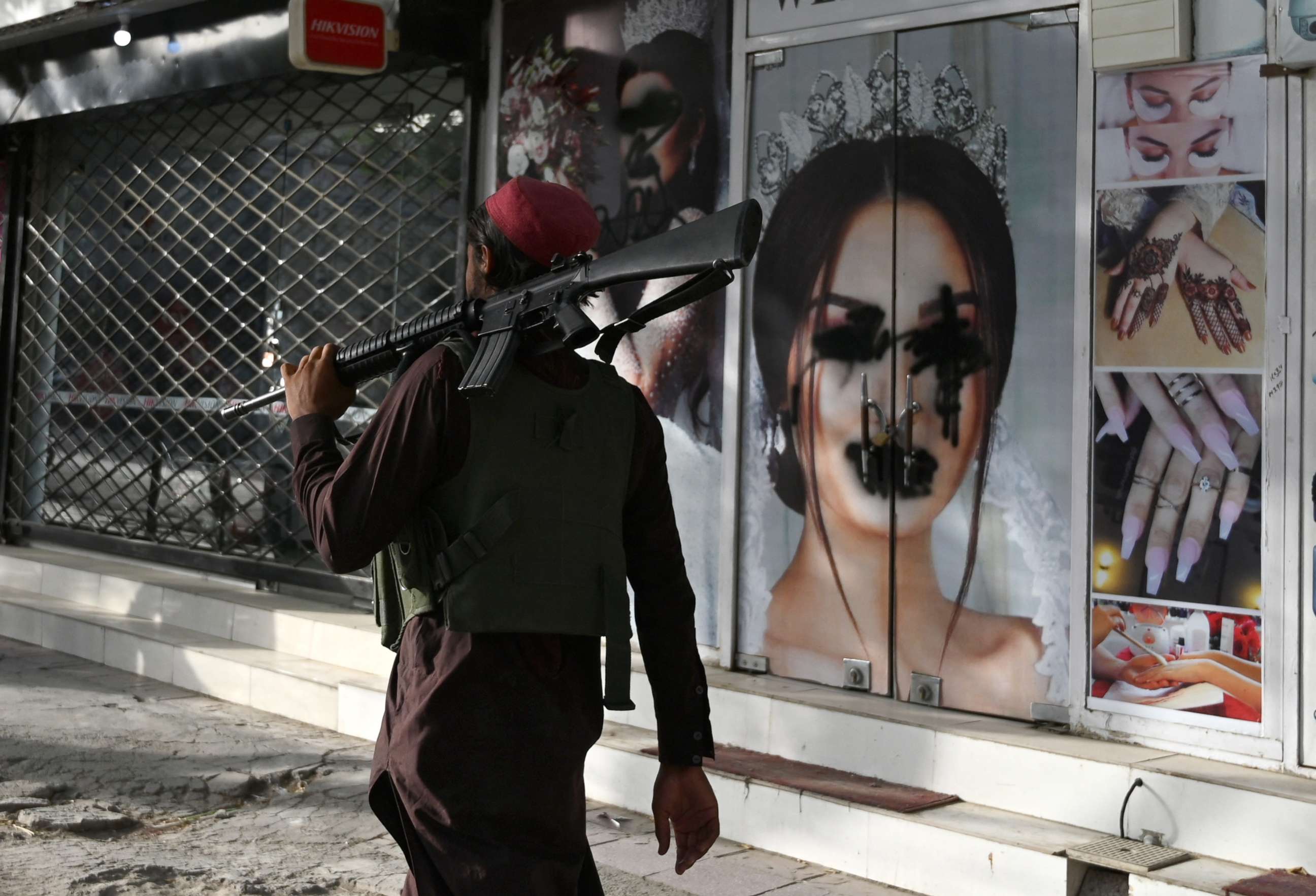 PHOTO: A Taliban fighter walks past a beauty salon with images of women defaced using spray paint in Kabul, Afghanistan, Aug. 18, 2021.
