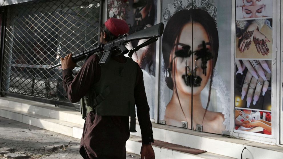 PHOTO: A Taliban fighter walks past a beauty salon with images of women defaced using spray paint in Kabul, Afghanistan, Aug. 18, 2021.