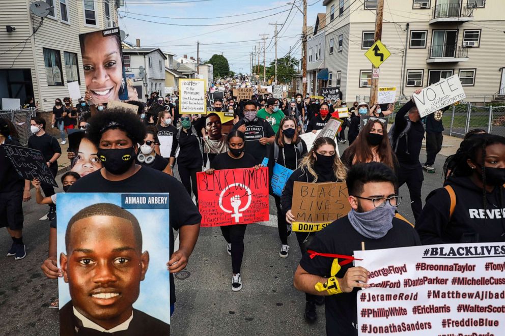 PHOTO: A marcher carries a sign with an image of Ahmaud Arbery, left, during a peaceful protest on June 9, 2020 in Revere, Mass., for Black Americans killed at the hands of law enforcement.